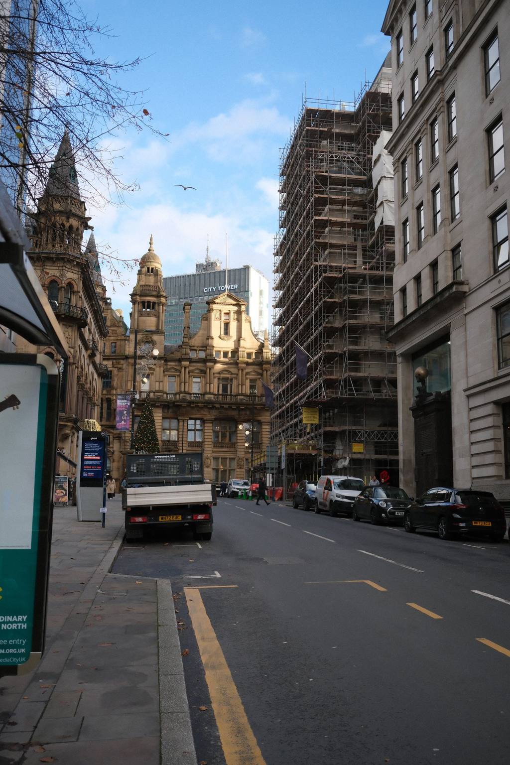 Street scene with historic brick architecture and construction scaffolding under a bright sky in Leeds